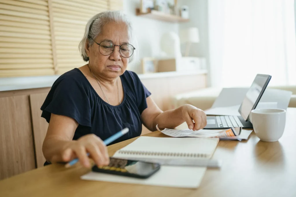Retired Singaporean woman organising monthly household expenses at home